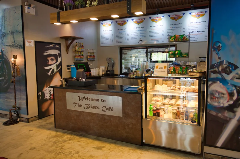 The coffee counter, under its Welcome to The Bikers Café plate and the menu boards